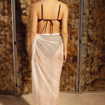 KABE SHOP INC Manita Pareo in sheer white crepe with gold-plated logo jewel, worn as a beach wrap by a model.