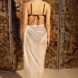 KABE SHOP INC Manita Pareo in sheer white crepe with gold-plated logo jewel, worn as a beach wrap by a model.
