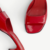 The Dona Mule is a pair of shiny red mule pumps featuring square toes and low heels, displayed from above on a white background.