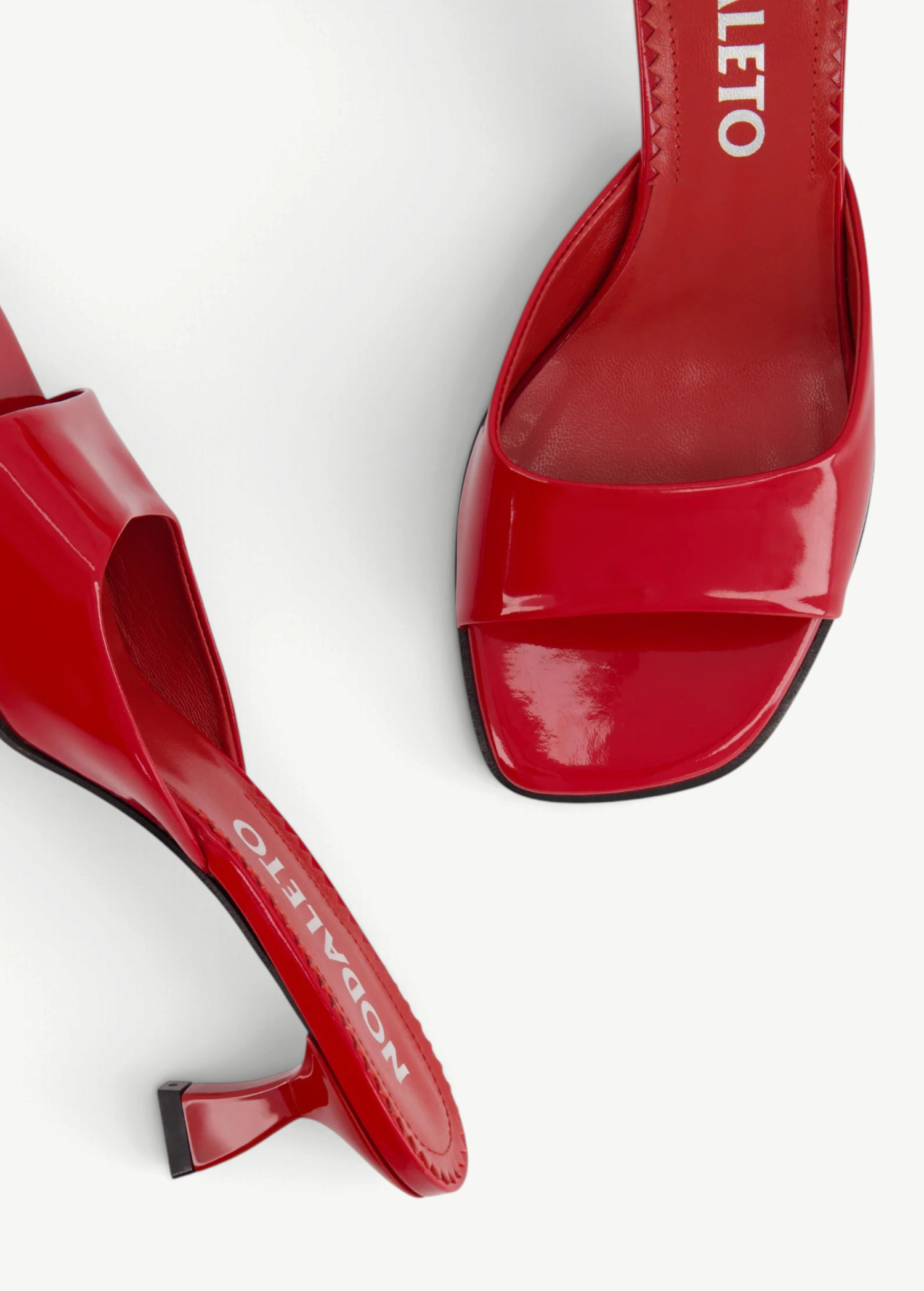 The Dona Mule is a pair of shiny red mule pumps featuring square toes and low heels, displayed from above on a white background.