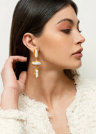 KABE SHOP INC Grace earrings featuring elongated baroque pearls in gold settings worn by a model in profile view