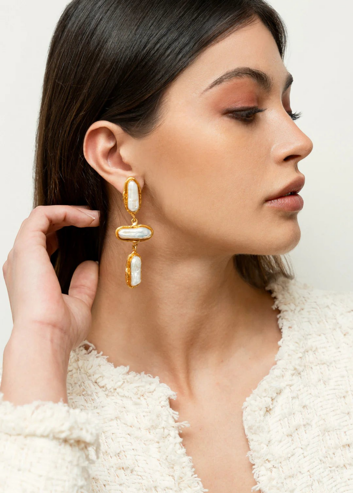 KABE SHOP INC Grace earrings featuring elongated baroque pearls in gold settings worn by a model in profile view