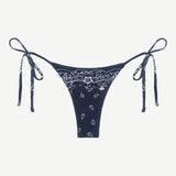 Praia Bottom in navy blue with a white paisley bandana print, crafted from eco-terry fabric, features a low-rise silhouette and adjustable side ties, shown on a white background.