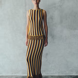 A woman wears a Misti Sleeveless Top paired with a matching maxi skirt featuring vertical stripes and fringed hems.