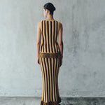 Back view of a person wearing a Misti Sleeveless Top and matching long skirt, both featuring vertical stripes in brown, yellow, and white with artisanal detailing at the fringe hems.