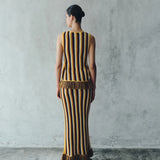 Back view of a person wearing a Misti Sleeveless Top and matching long skirt, both featuring vertical stripes in brown, yellow, and white with artisanal detailing at the fringe hems.
