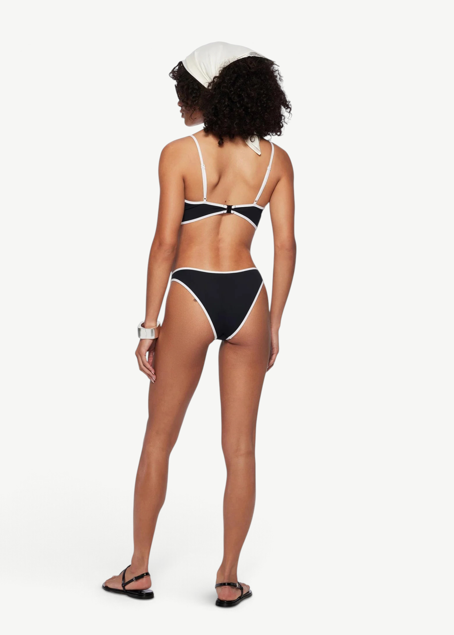 Model wearing KABE SHOP INC Ursula low-rise black bikini bottom with white trim from a back view