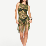 A woman poses against a plain white background in the Castaway Dress—a neon green and black macrame tunic style worn over a black bikini. She completes the look with sunglasses, sandals, and a confident hand on her hip.