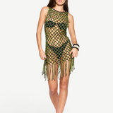 A woman poses against a plain white background in the Castaway Dress—a neon green and black macrame tunic style worn over a black bikini. She completes the look with sunglasses, sandals, and a confident hand on her hip.