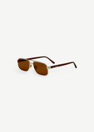 The Evangeline sunglasses feature brown lenses, thin gold stainless steel frames, and dark arms, offering reliable UV protection—all shown against a white background.