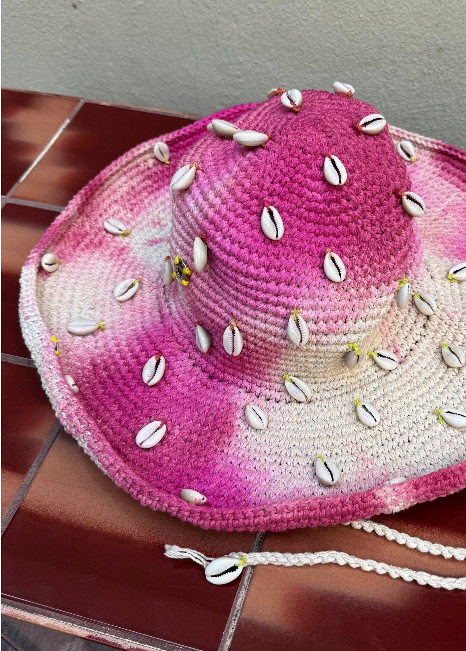 KABE SHOP INC Wika crochet hat in pink and white tie-dye featuring decorative cowrie shells and a chin strap