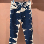 KABE SHOP INC tie dye denim jeans with a dark blue and bleached white abstract pattern hanging on a clothes hanger.