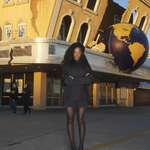 A model wearing KABE SHOP INC black tailored boxer shorts with a matching jacket and sheer tights outdoors.