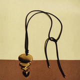 KABE SHOP INC gold pendant necklace featuring a sculptural layered design on a long black cord