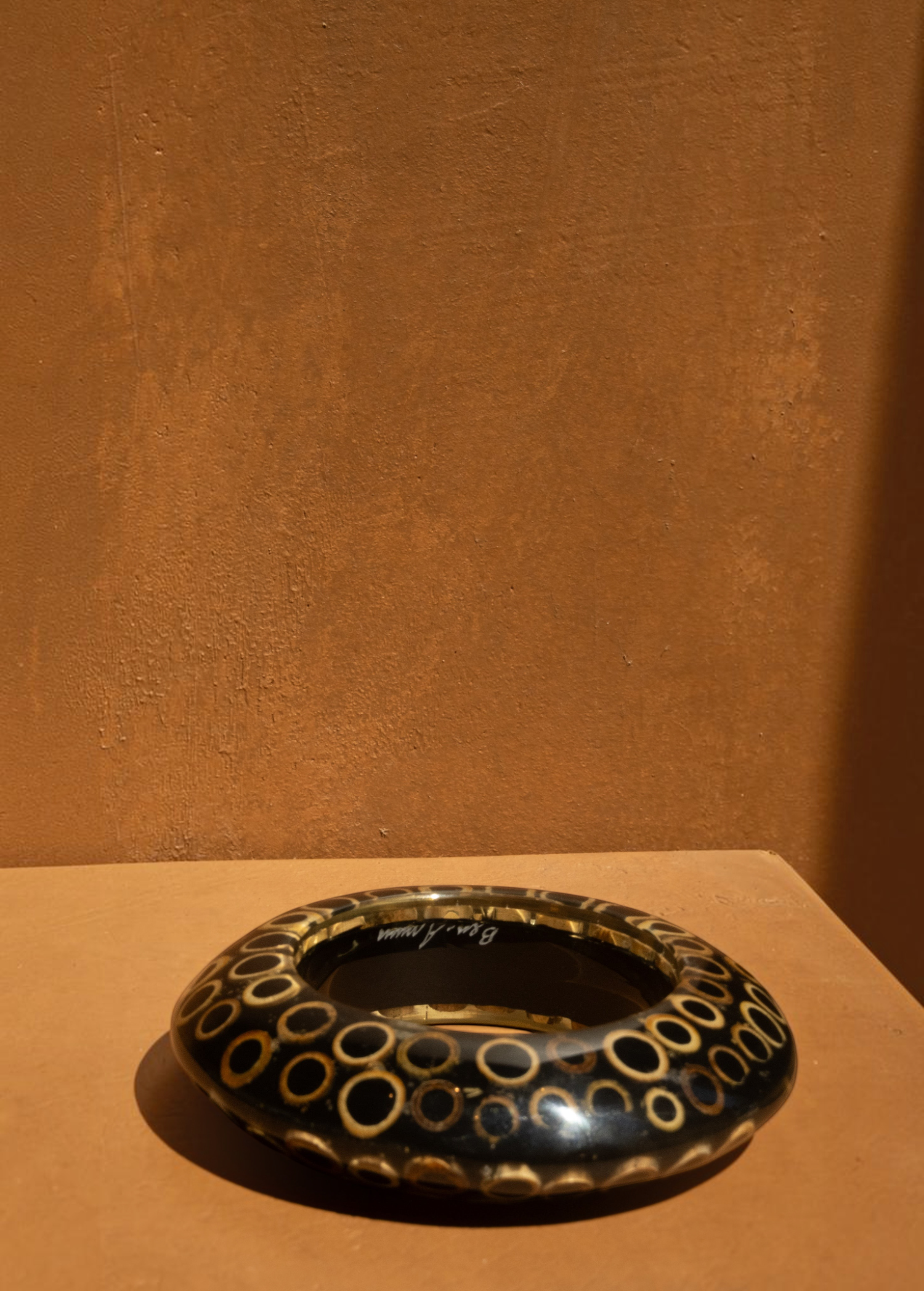 KABE SHOP INC wood and resin bangle featuring a black and tan circular pattern in a sculptural, modern design.