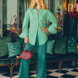 Model wearing KABE SHOP INC Pia Poplin Pants in a vibrant green and blue stripe with a matching button-down shirt.