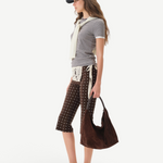Model wearing KABE SHOP INC Gianna Pants featuring a brown polka dot print, flared silhouette, and crochet detail.