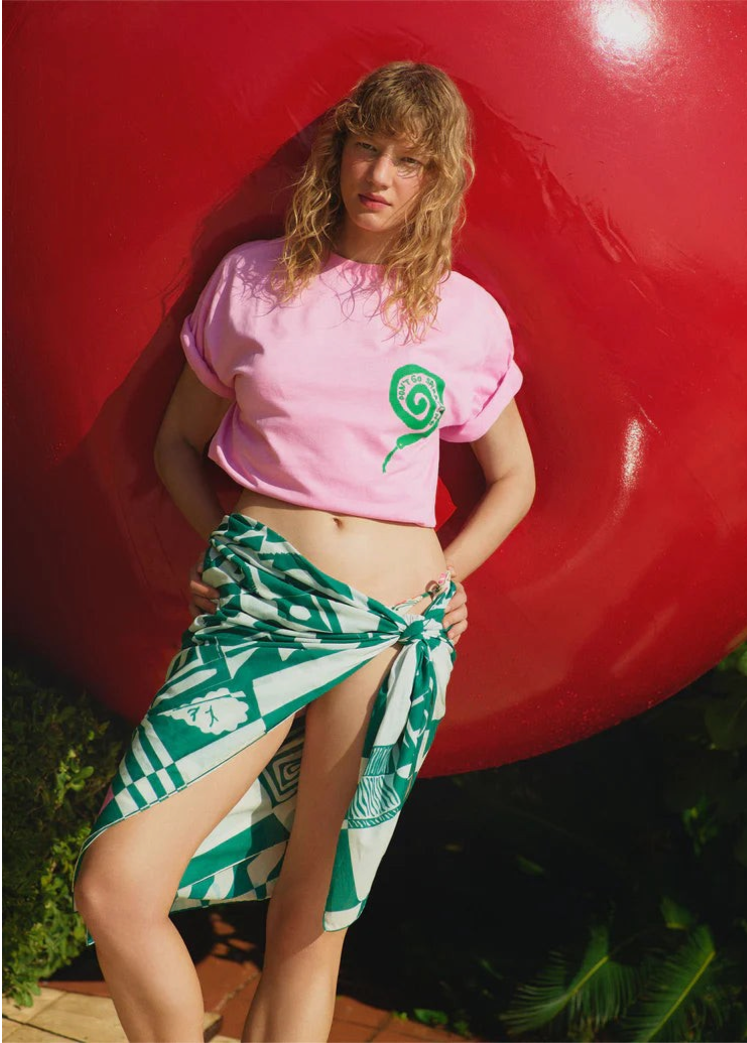 Model wearing a KABE SHOP INC Grass Seeds Pareo with a green geometric print, styled as a beach cover-up.