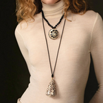 KABE SHOP INC Marble Cone Shell Necklace on a leather cord with gold accents worn by a woman in a cream turtleneck.