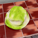 KABE SHOP INC handmade crochet bucket hat with a vibrant green and white tie-dye pattern on a red tiled surface
