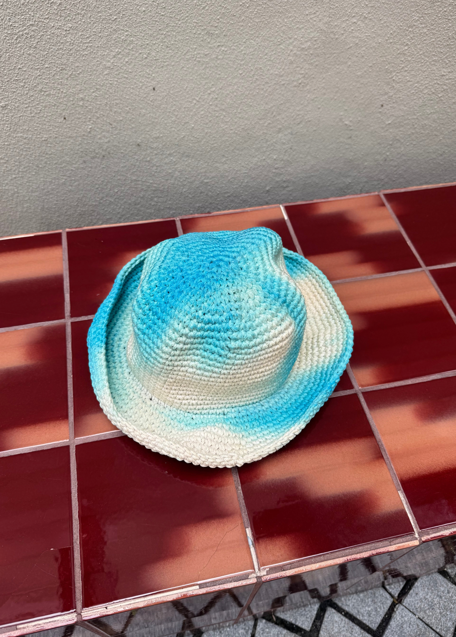 KABE SHOP INC Pora crochet hat featuring a blue and white tie-dye pattern on a textured handmade surface.