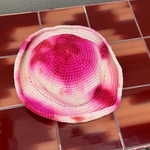 KABE SHOP INC handmade crochet bucket hat featuring a vibrant pink and white tie-dye pattern on a tiled surface.