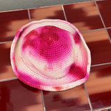 KABE SHOP INC handmade crochet bucket hat featuring a vibrant pink and white tie-dye pattern on a tiled surface.