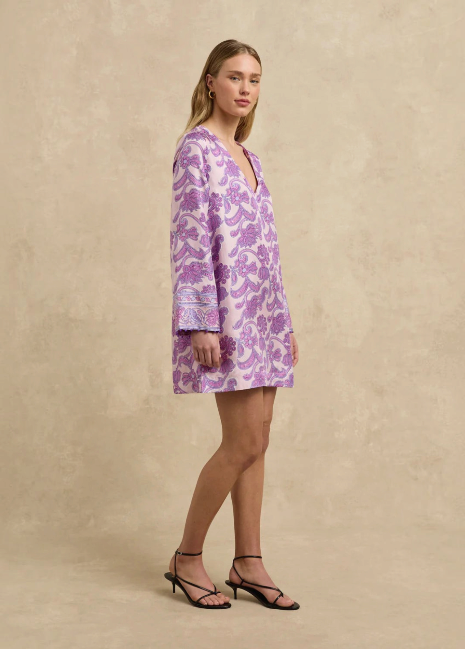 Model wearing KABE SHOP INC Jaya tunic dress in light pink and purple paisley print with long sleeves