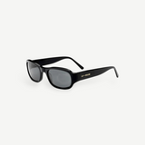 The Jordyn sunglasses are black, rectangular-shaped with thick frames and dark lenses. LU GOLDIE’s name appears in gold lettering on the arms. Displayed against a plain white background, these standout festival sunglasses provide reliable UV protection for sunny days outdoors.
