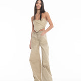 A woman stands against a white background, wearing Cold Dye Boyfriend Jeans with patch pockets, styled with a beige strapless top and green sandals. She has long, straight hair and her hands rest casually in her pockets.