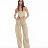 A woman stands against a white background, wearing a beige strapless top and Cold Dye Boyfriend Jeans with Patch Pockets featuring visible pockets and wide legs. She has long straight hair and her hands are tucked into her pockets.