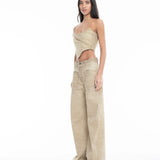 A woman with long hair wears a tan, asymmetrical strapless top and Cold Dye Boyfriend Jeans with Patch Pockets, which feature wide legs and a stylish patch pocket. She stands facing slightly left against a plain white background.