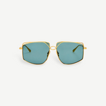 The Miranda Sunglasses feature an oversized, geometric frame expertly crafted from Japanese titanium with a luxurious gold-plated finish and distinctive blue-green tinted lenses, shown facing forward against a plain white background.