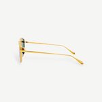 Side view of Miranda Sunglasses, featuring gold-plated frames with green lenses, displayed against a plain white background. The thin Japanese titanium arms are gently curved at the ends, enhancing the modern, sleek look of the oversized design.