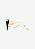 Side view of the Macy Sunglasses with gold geometric temples and black oversized frames, featuring aqua gradient lenses, displayed on a plain white background.