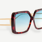 Close-up of the Macy Sunglasses featuring oversized square tortoiseshell acetate frames, gold metal arms, and aqua gradient lenses against a white background.