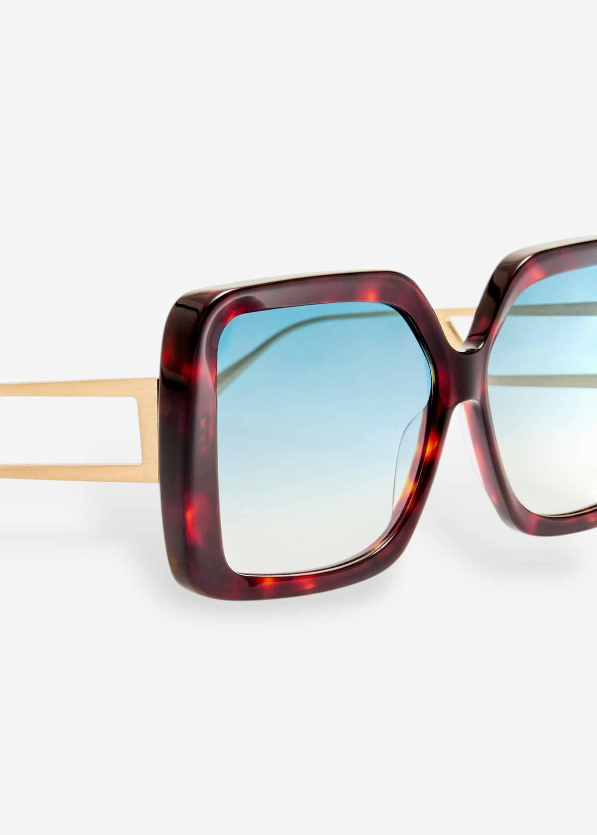 Close-up of the Macy Sunglasses featuring oversized square tortoiseshell acetate frames, gold metal arms, and aqua gradient lenses against a white background.