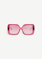 Front view of the Macy Sunglasses, showcasing oversized, square-shaped frames crafted from luxurious Italian acetate in translucent pink, complemented by matching pink-tinted lenses and elegant gold plated temples, set against a plain white background.