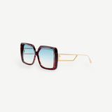 The Macy Sunglasses feature oversized square frames crafted from red tortoiseshell acetate, paired with thin gold arms and aqua gradient lenses, displayed on a white background.