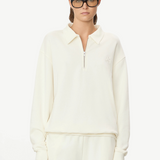 Model wearing a KABE SHOP INC cream oversized French terry half-zip polo sweatshirt with a collar and zip closure.