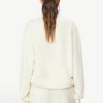 Back view of a woman wearing a KABE SHOP INC oversized cream French terry zip-up polo sweatshirt with long sleeves.