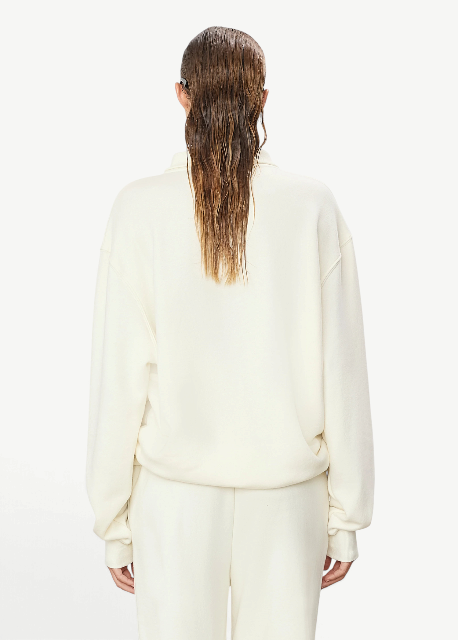 Back view of a woman wearing a KABE SHOP INC oversized cream French terry zip-up polo sweatshirt with long sleeves.