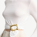 KABE SHOP INC Sculpted Slide featuring a polished gold square ring cinching a white long-sleeve top at the waist.