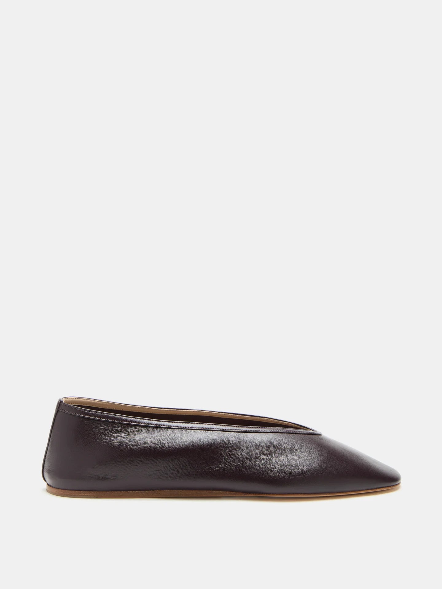 A single Luna Slipper Shoe in dark brown, crafted from supple plum lambskin with minimalist seamless leather detailing and a slightly pointed toe, is displayed in side profile against a plain white background.