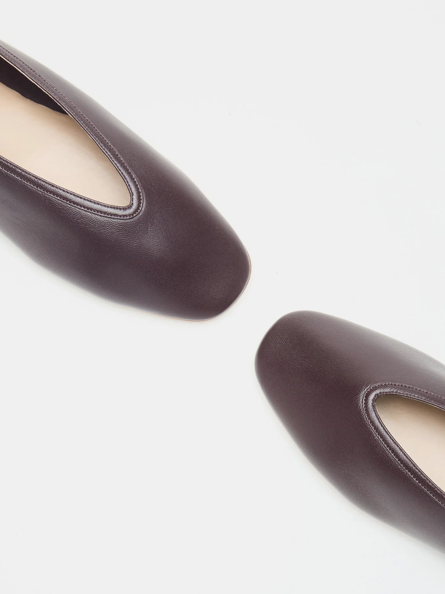 Two Luna Slipper Shoes in dark brown leather with rounded square toes and refined leather detailing, positioned diagonally on a white background.