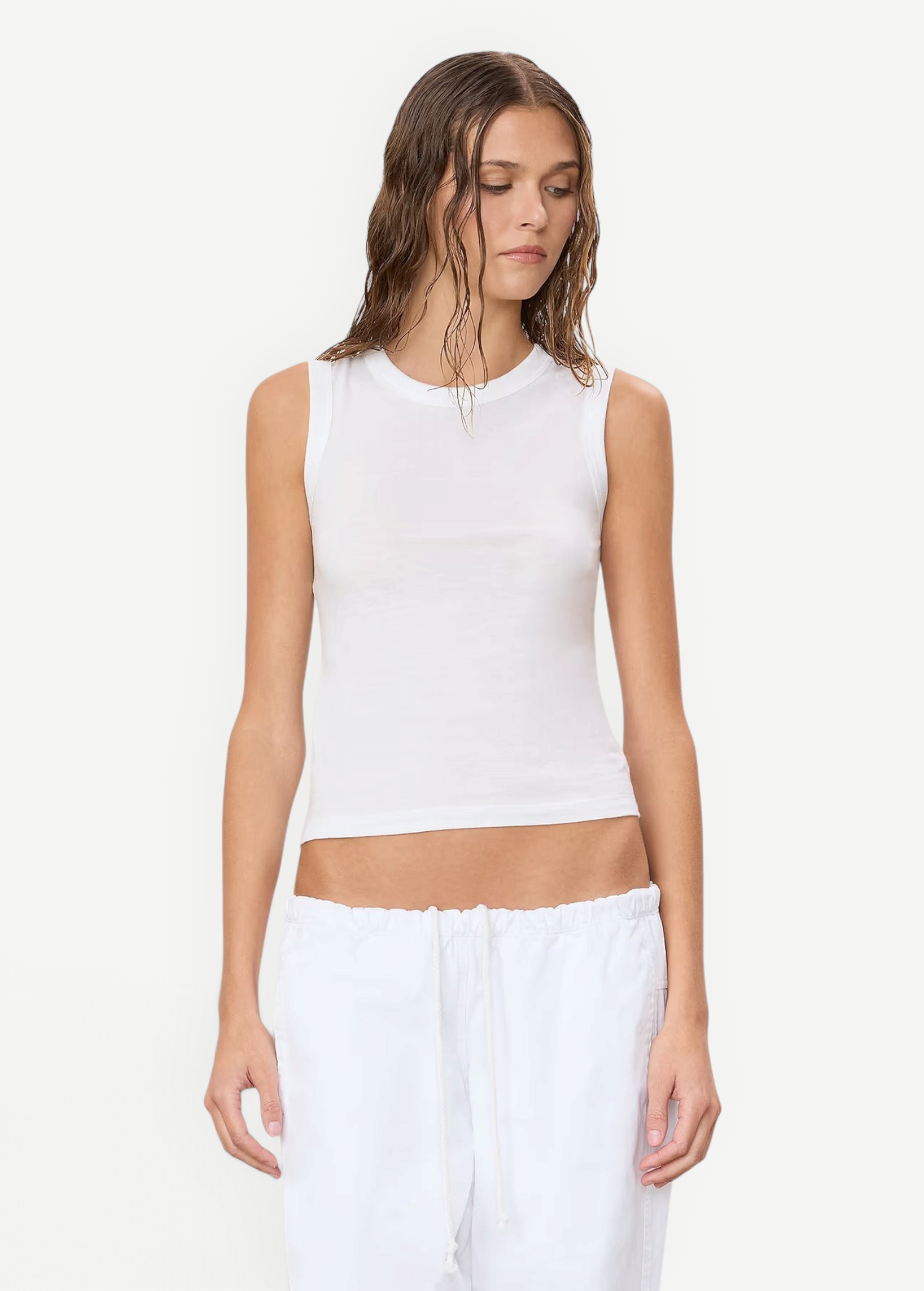 A woman wears a white, sleeveless, round-neck Fitted Muscle Tank.