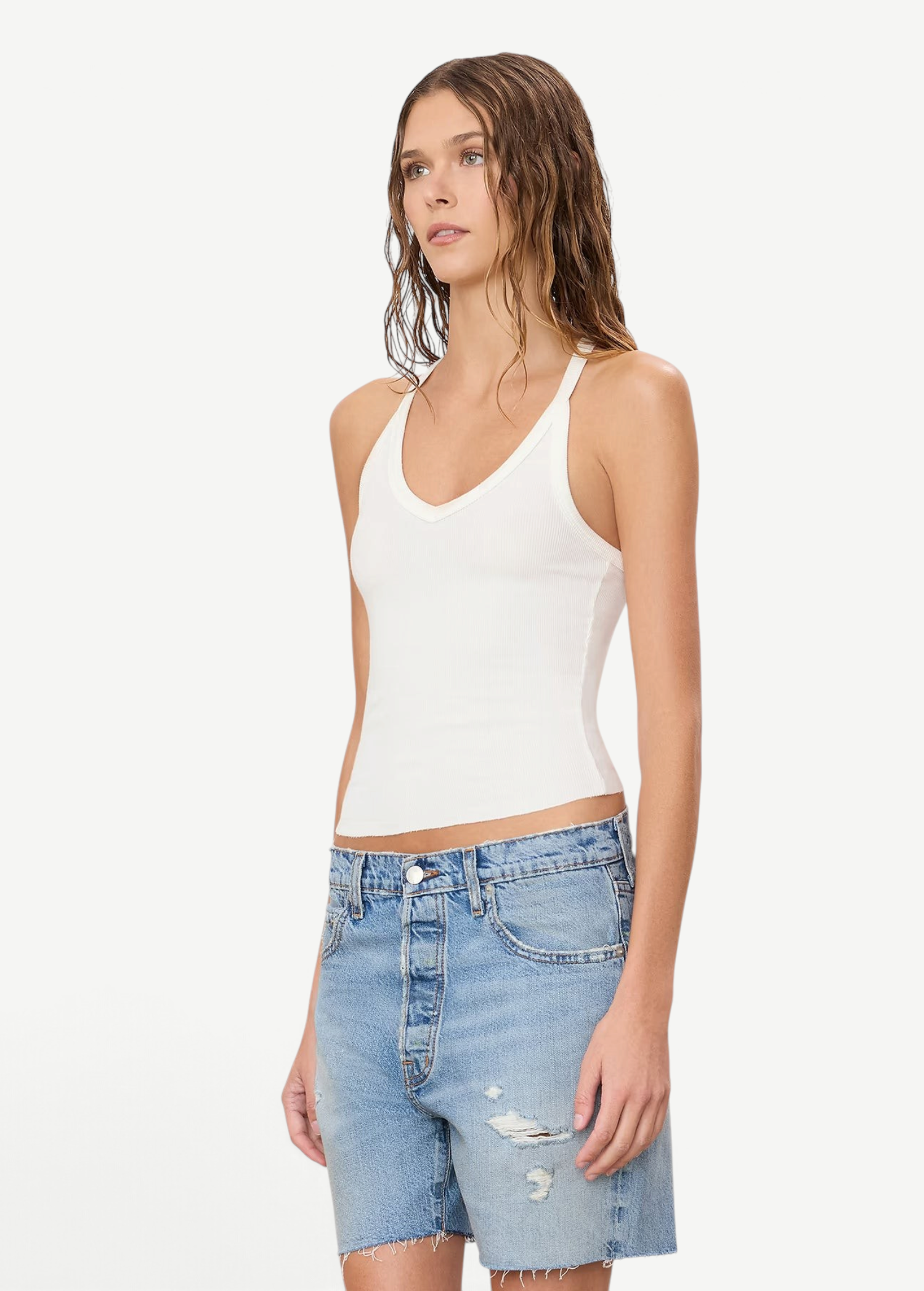 Model wearing a white KABE SHOP INC ribbed V-neck racerback tank top with a slim fit, paired with denim shorts.