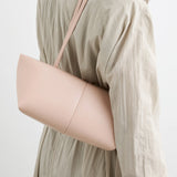A person is shown from the back against a plain white background, wearing a beige trench coat and carrying the Boulevard Sling Bag in pale pink nappa leather over their shoulder.