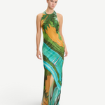 Model wearing KABE SHOP INC Magdalena long silk maxi dress with halter neckline and landscape print in green and gold