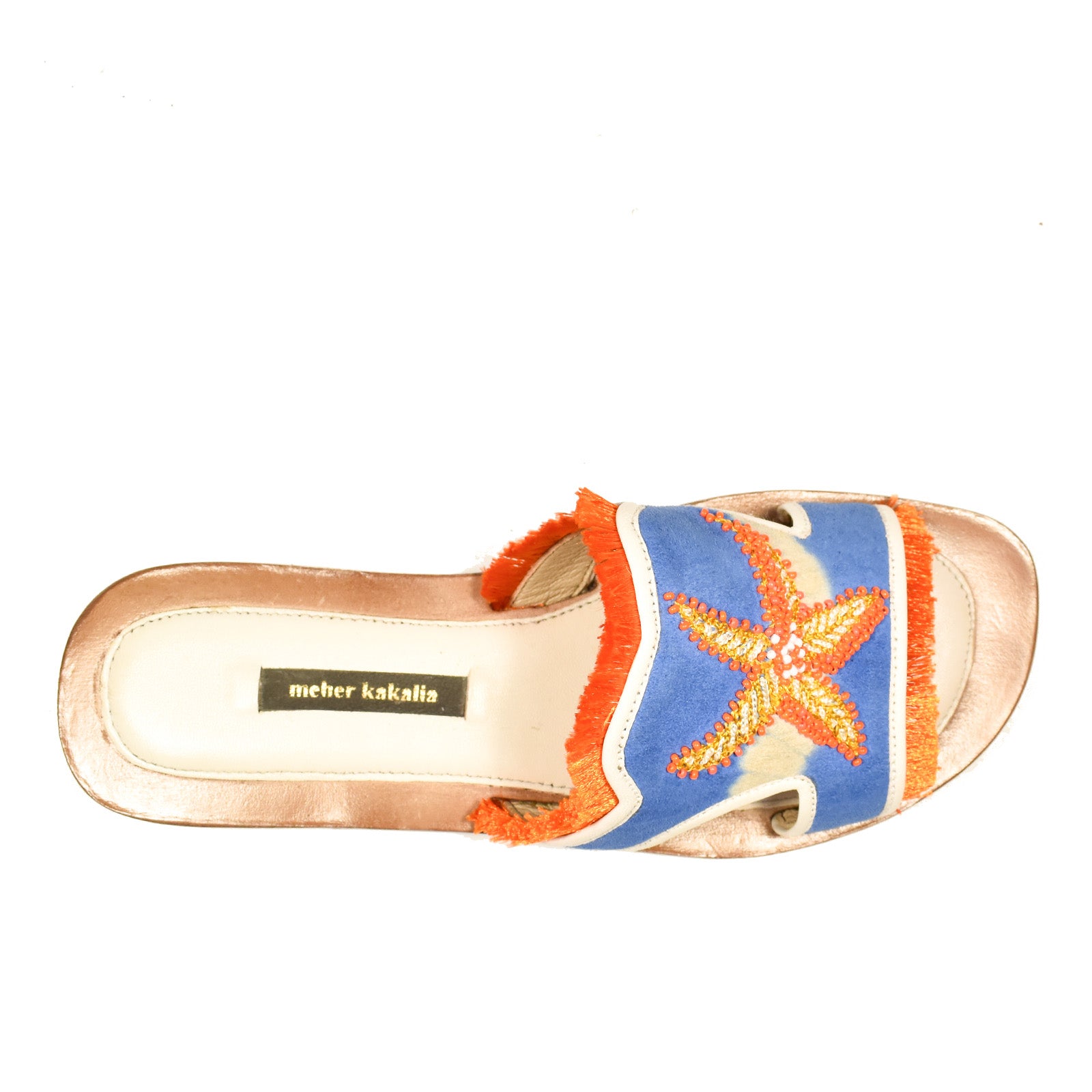 Introducing the Mazu Slide: a single slip-on sandal featuring a gold sole, blue fabric upper, orange fringe trim, and an embroidered orange starfish design—each pair embodies the unique craftsmanship and charm of Silk Route artisans.